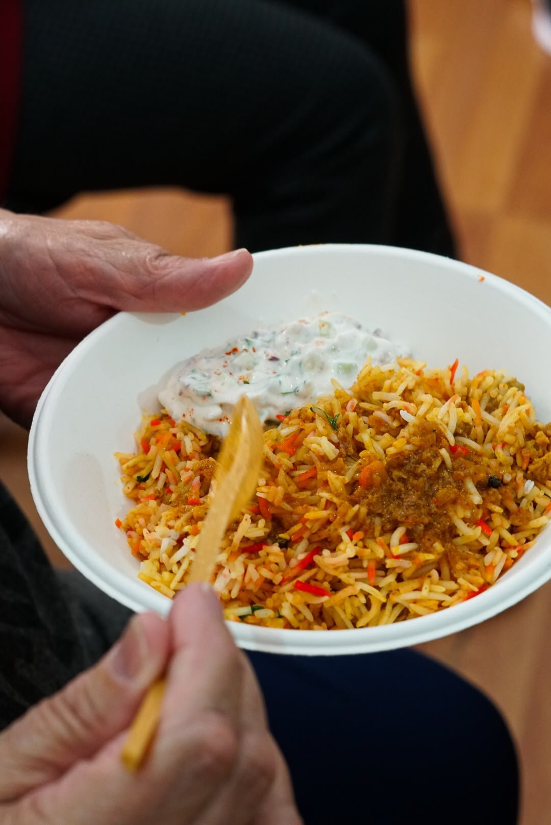Prato de arroz com especiarias e raita seguro numa mão
