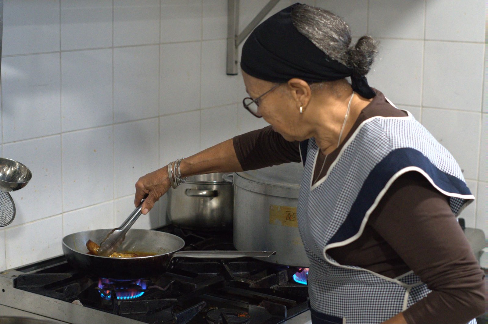 Cozinheira ao fogão a fritar numa frigideira